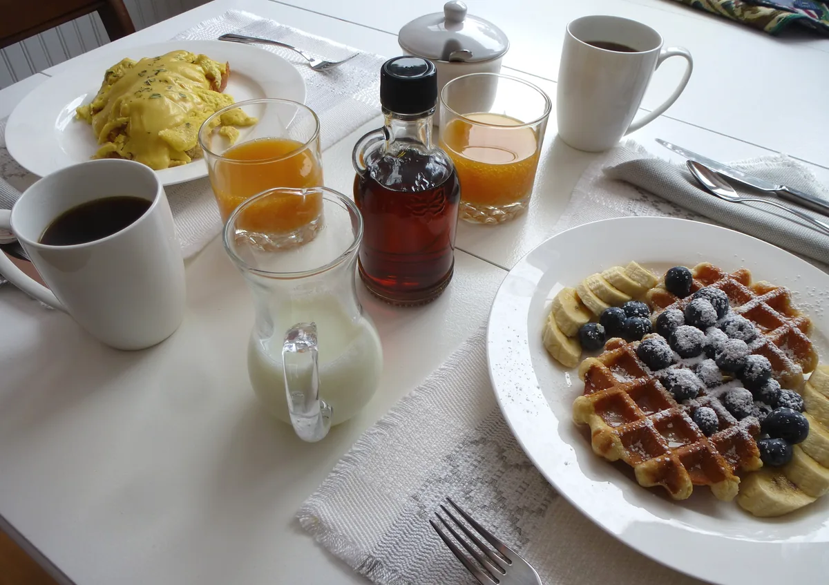 Waffles with blueberries and banana beside scrambled eggs with tarragon hollandaise